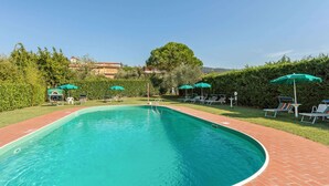 A rectangular swimming pool with a brick border, surrounded by lounge chairs and umbrellas, and a hedge in the background. - Nice Apartment in Tuoro sul Trasimeno With Pool (Tuoro sul Trasimeno)
