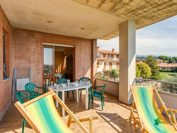 A balcony with a table and chairs, a view of the surrounding buildings, and a wooden deck. - Nice Apartment in Tuoro sul Trasimeno With Pool (Tuoro sul Trasimeno)