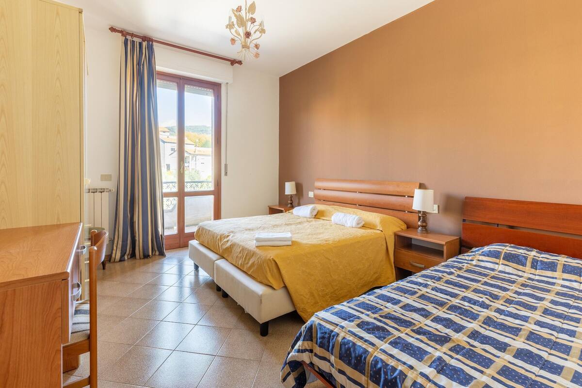 Ein Hotelzimmer mit Bett, Nachttischen, einem Schreibtisch und Blick durch ein Fenster.