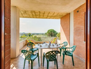 A balcony with a table and chairs, a view of the countryside, and a brick wall. - Nice Apartment in Tuoro sul Trasimeno With Pool (Tuoro sul Trasimeno)