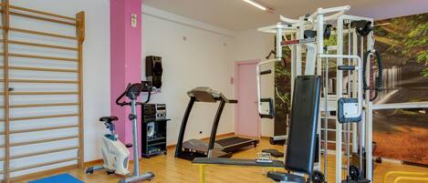 A gym with exercise equipment, a treadmill, and a blue mat.