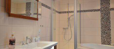 A bathroom with a shower, a sink, and a mirror.