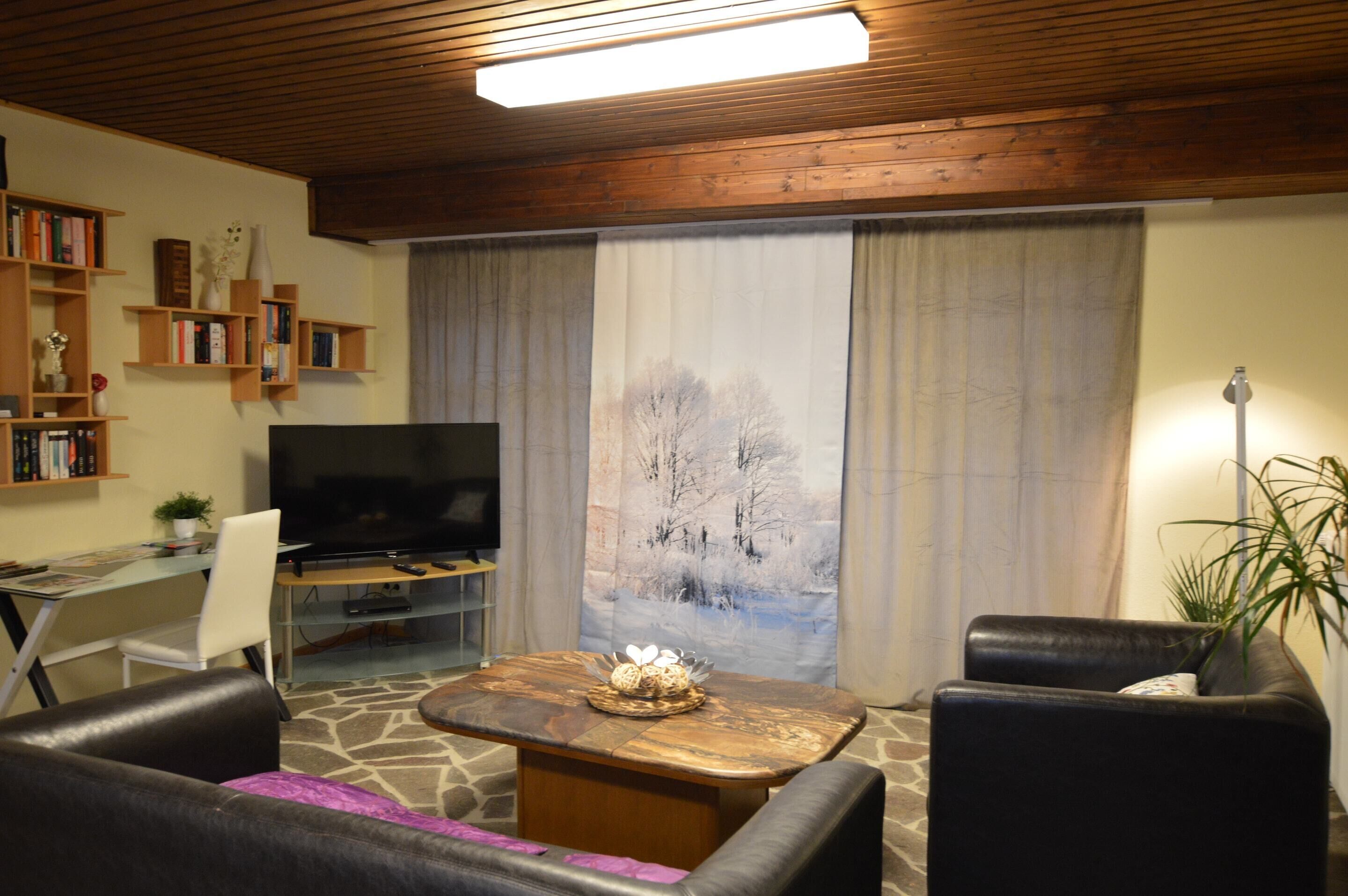 A living room with a television, a coffee table, and a bookshelf.