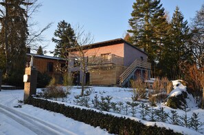 A wooden house with a brick section, surrounded by snow and trees. - Cosy Apartment in Manderscheid With Balcony (Manderscheid)