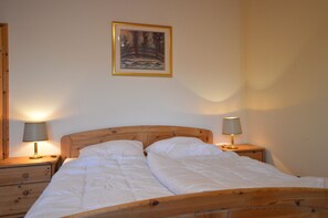 A double bed with wooden headboard, two bedside tables with lamps, and a framed picture on the wall. - Cosy Apartment in Manderscheid With Balcony (Manderscheid)
