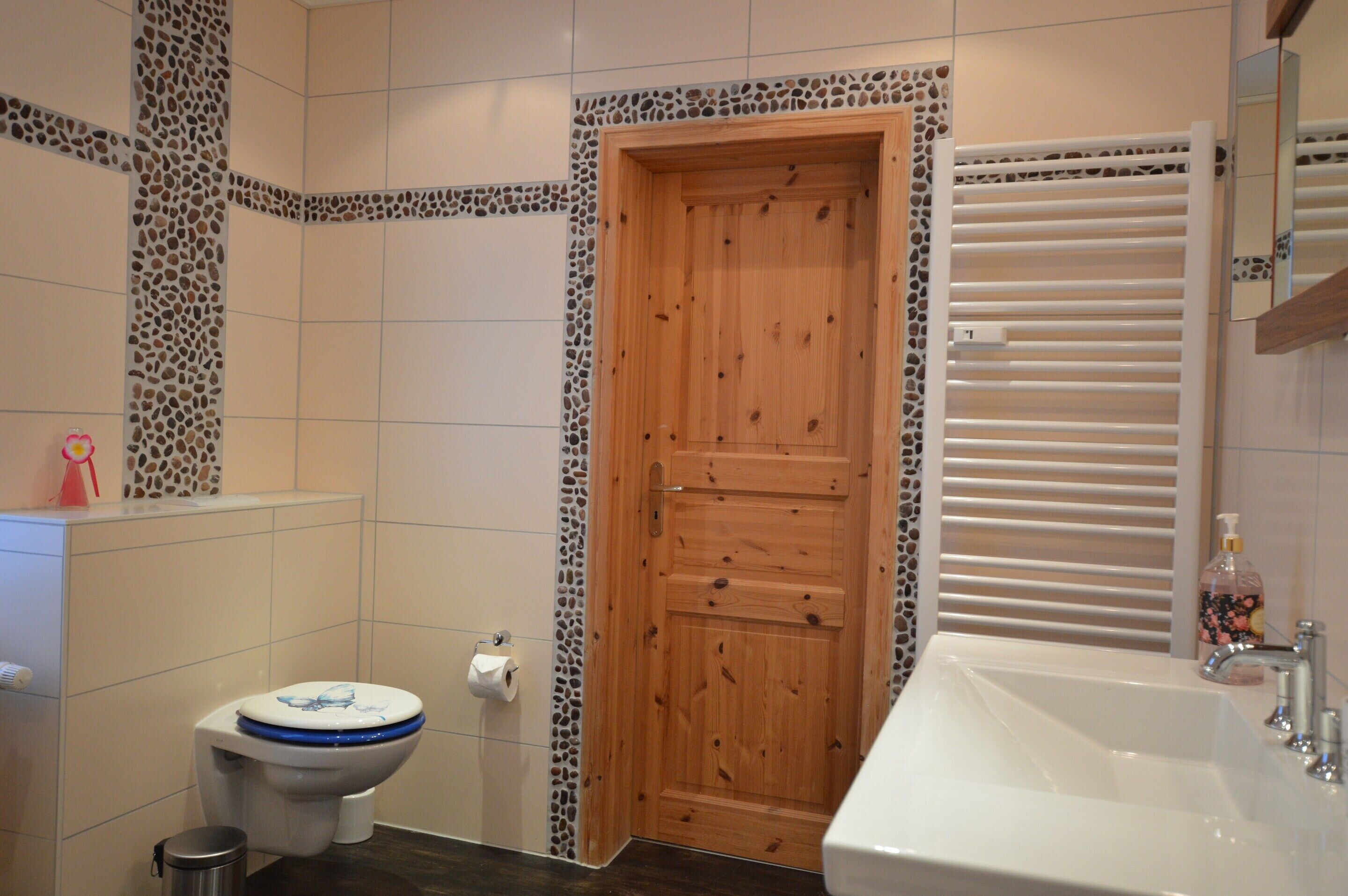 Une salle de bain avec une porte en bois, des toilettes, un lavabo et un miroir.