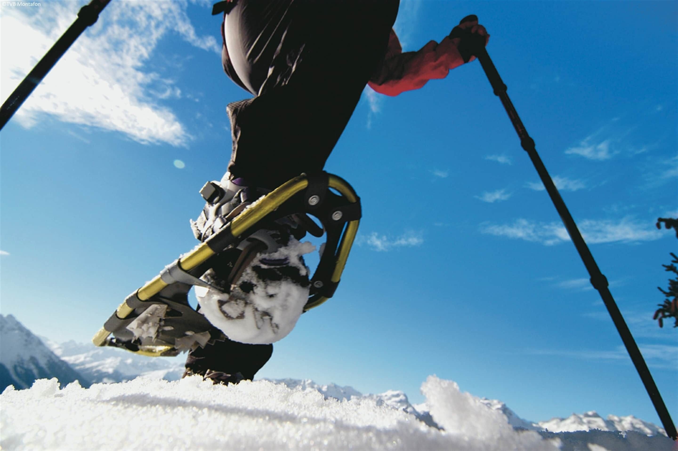 A person using ski-like mechanical legs on snowy terrain with a clear sky.
