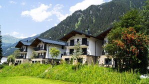 A modern multi-story hotel with balconies, set against a mountainous backdrop. - Chalet Montafon in Gaschurn With Sauna (Gaschurn)