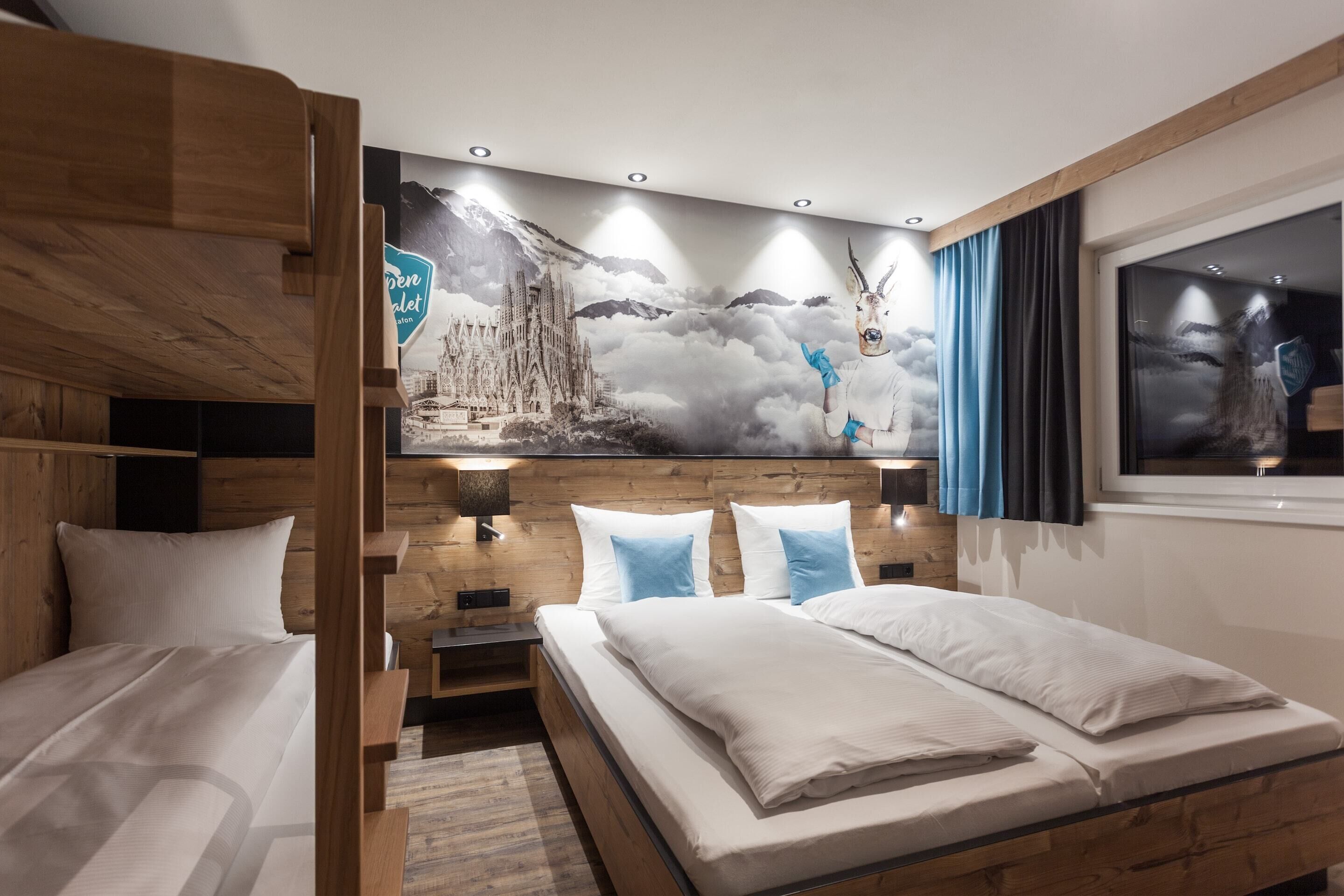 A hotel room with a bunk bed, a large mural, a window with curtains, and a nightstand.