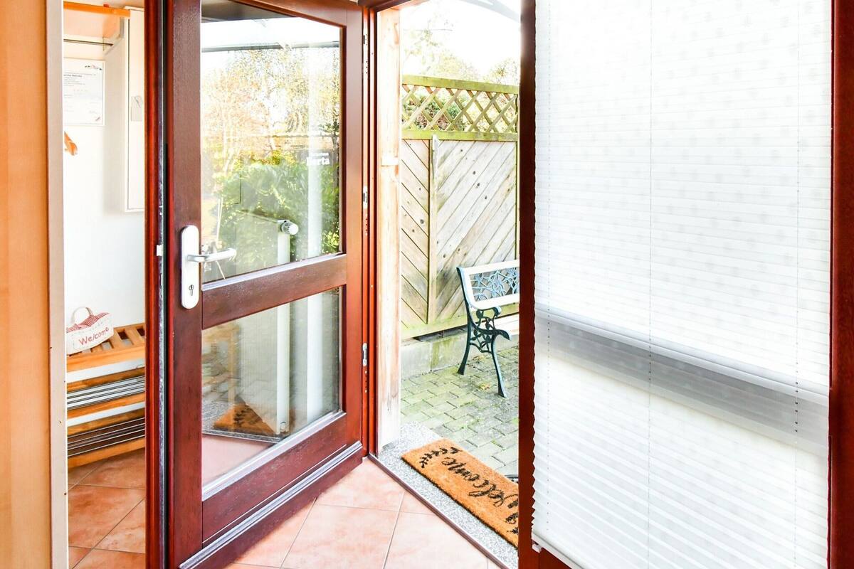 A sliding glass door leading to a patio area with a wooden fence and a bench.
