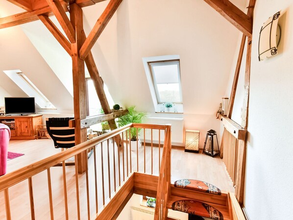 A loft-style room with a wooden staircase, a television, a desk, and a window. - Fabelhaftes Ferienhaus in Thorstorf in Meeresnaehe (Warnow)