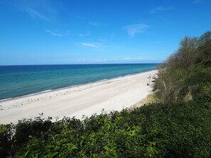 A beach with clear blue water and a sandy shore.