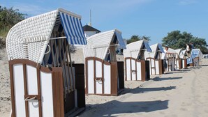 Beach huts with striped awnings and wooden frames, arranged in a row on a sandy beach. - Cozy Holiday Home in Rerik With Terrace (Rerik)