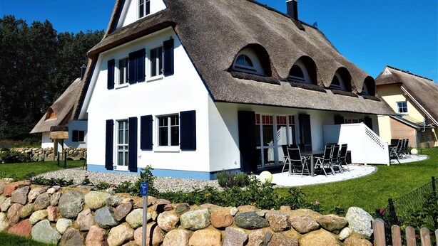 A traditional house with a steep thatched roof, multiple windows, and a stone wall in the foreground. - Cozy Holiday Home in Rerik With Terrace (Rerik)