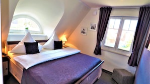 A bedroom with a bed, a nightstand, a lamp, a window with curtains, and a small table. - Cozy Holiday Home in Rerik With Terrace (Rerik)