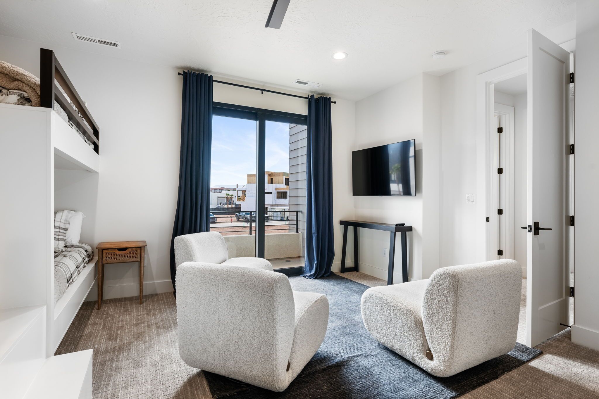 A modern hotel room with a balcony, a flat-screen TV, and a sofa.
