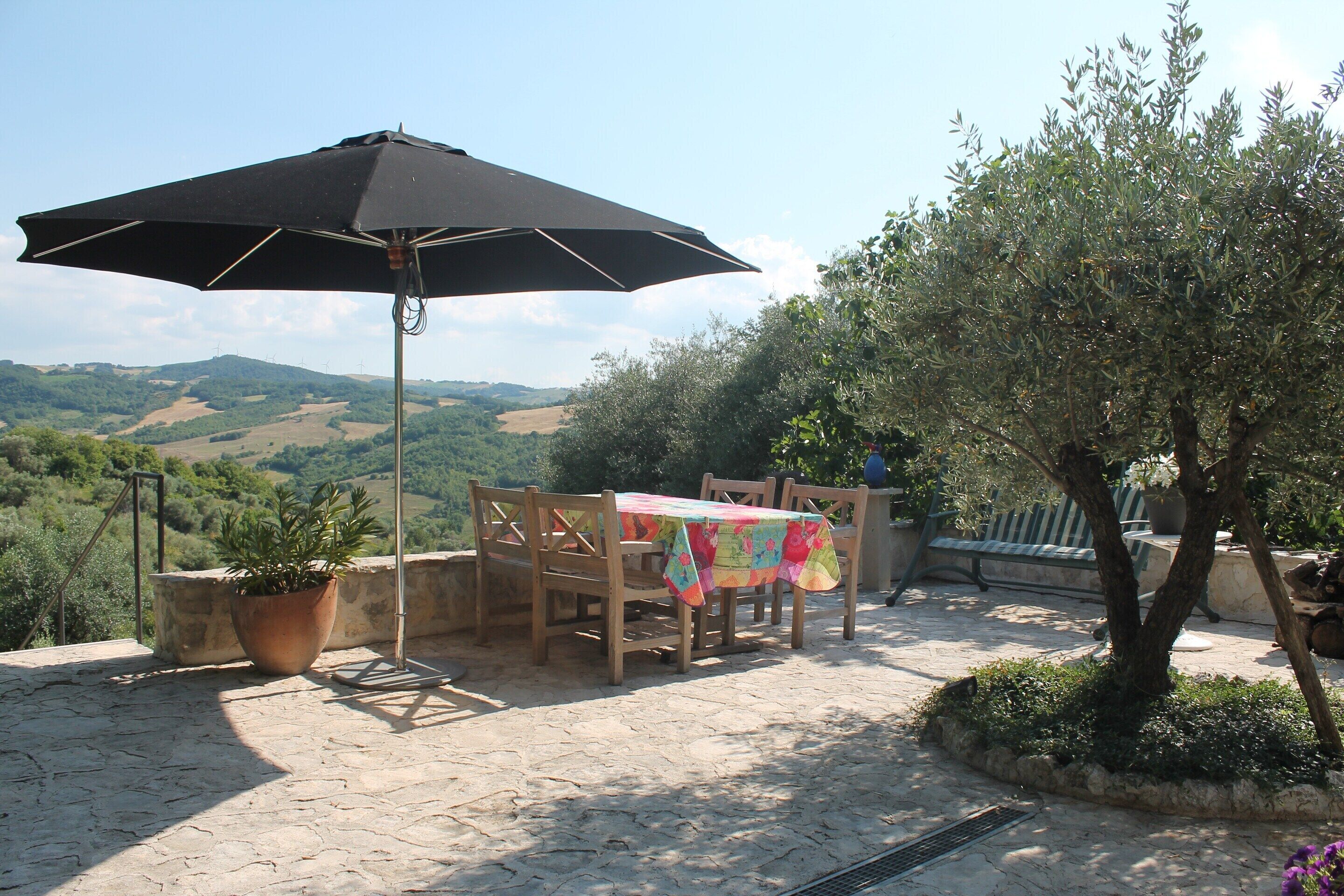 An outdoor patio with a table, chairs, and a large umbrella.