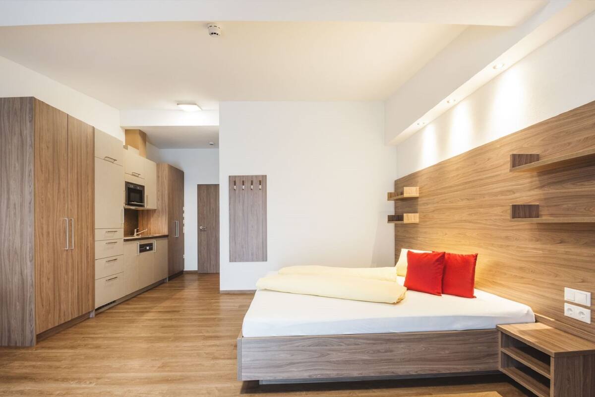 A modern bedroom with a wooden bed frame, a built-in wardrobe, and a bedside table.