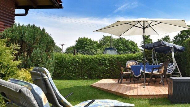 Un patio con mobili da esterno, tra cui poltrone relax e un tavolo con ombrellone.