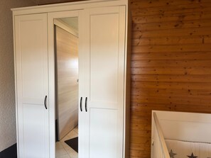 A room with a white wardrobe, wooden panel walls, and a visible hallway. - Ferienhaus in Altenfeld Thuringen mit Garten (Grossbreitenbach)