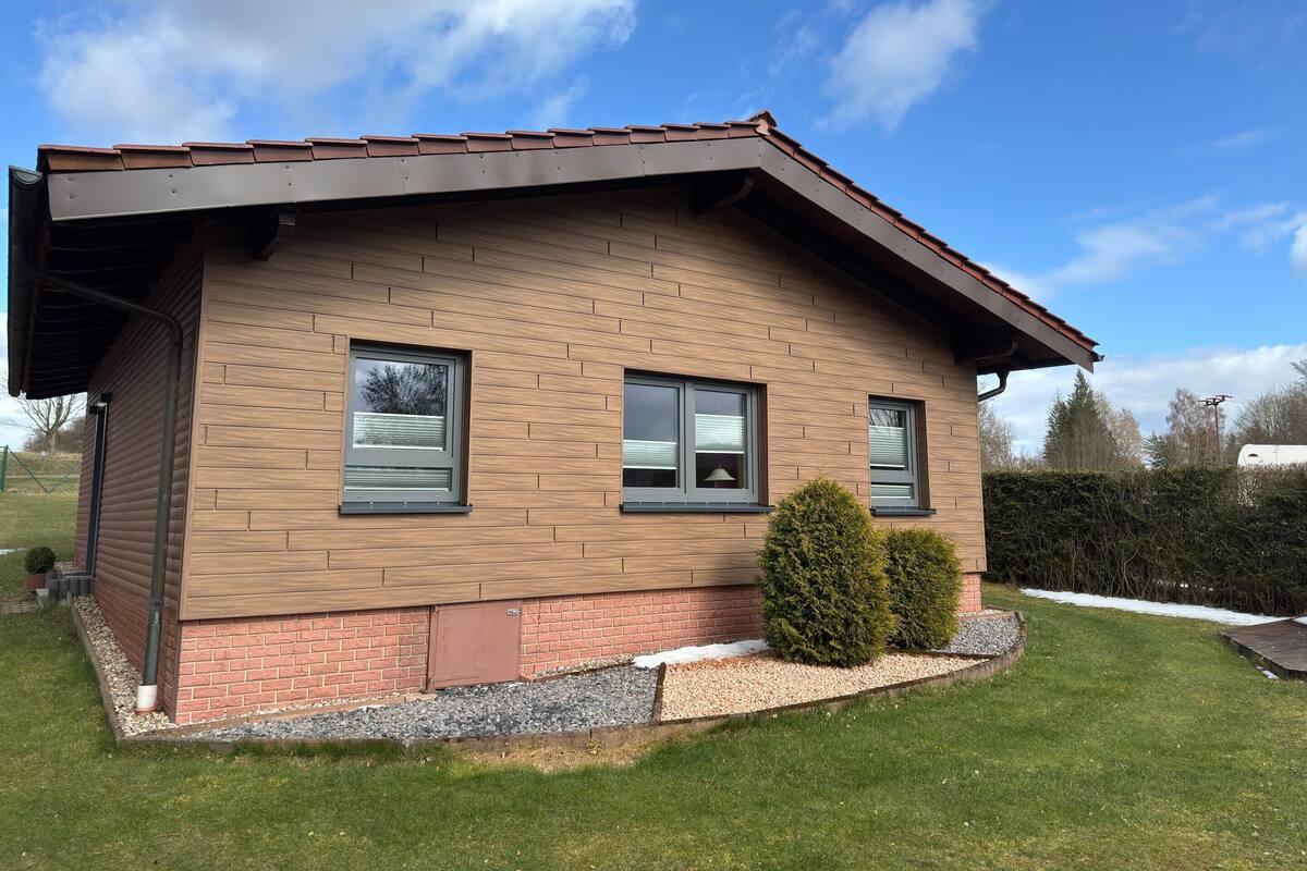A modern two-story house with a brick facade, large windows, and a well-maintained lawn.