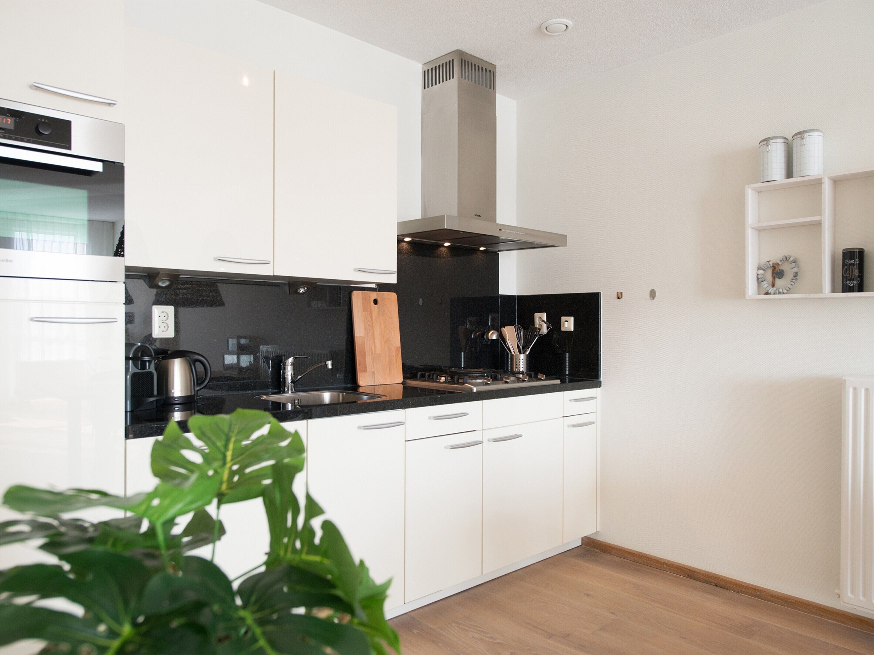 A modern kitchen with white cabinets, a black countertop, stainless steel appliances, and a central island with a knife block.