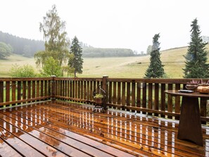 Une terrasse en bois offrant une vue sur un champ verdoyant et des arbres.