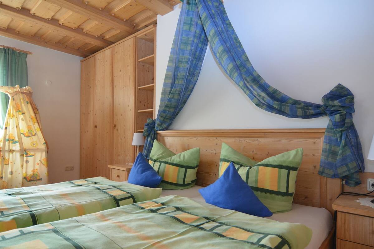 A room with two beds, wooden headboards, and a canopy.