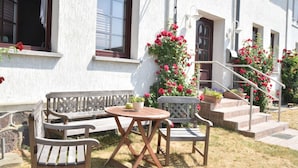 A patio with a wooden bench and table, surrounded by potted plants and flowers. - Inviting Apartment in Wendelstorf With Communal Garden (Bastorf)