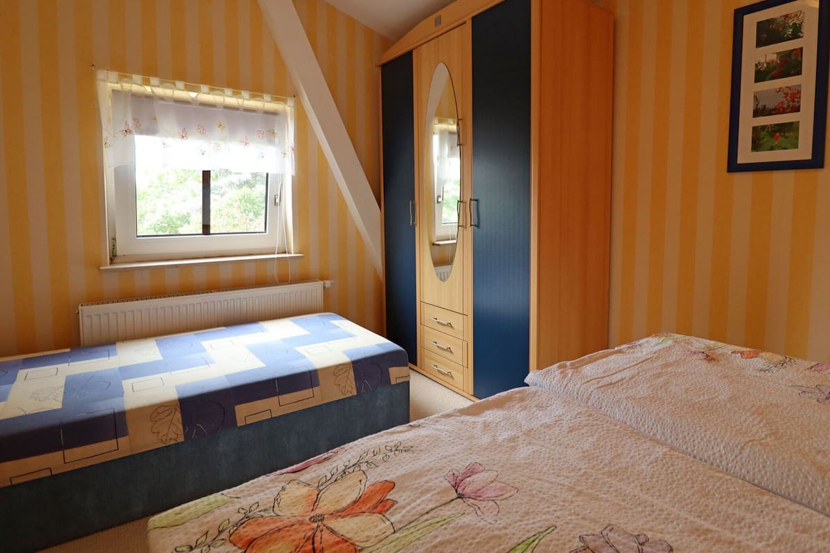 A bedroom with a bed, a window, a wardrobe, and a radiator.