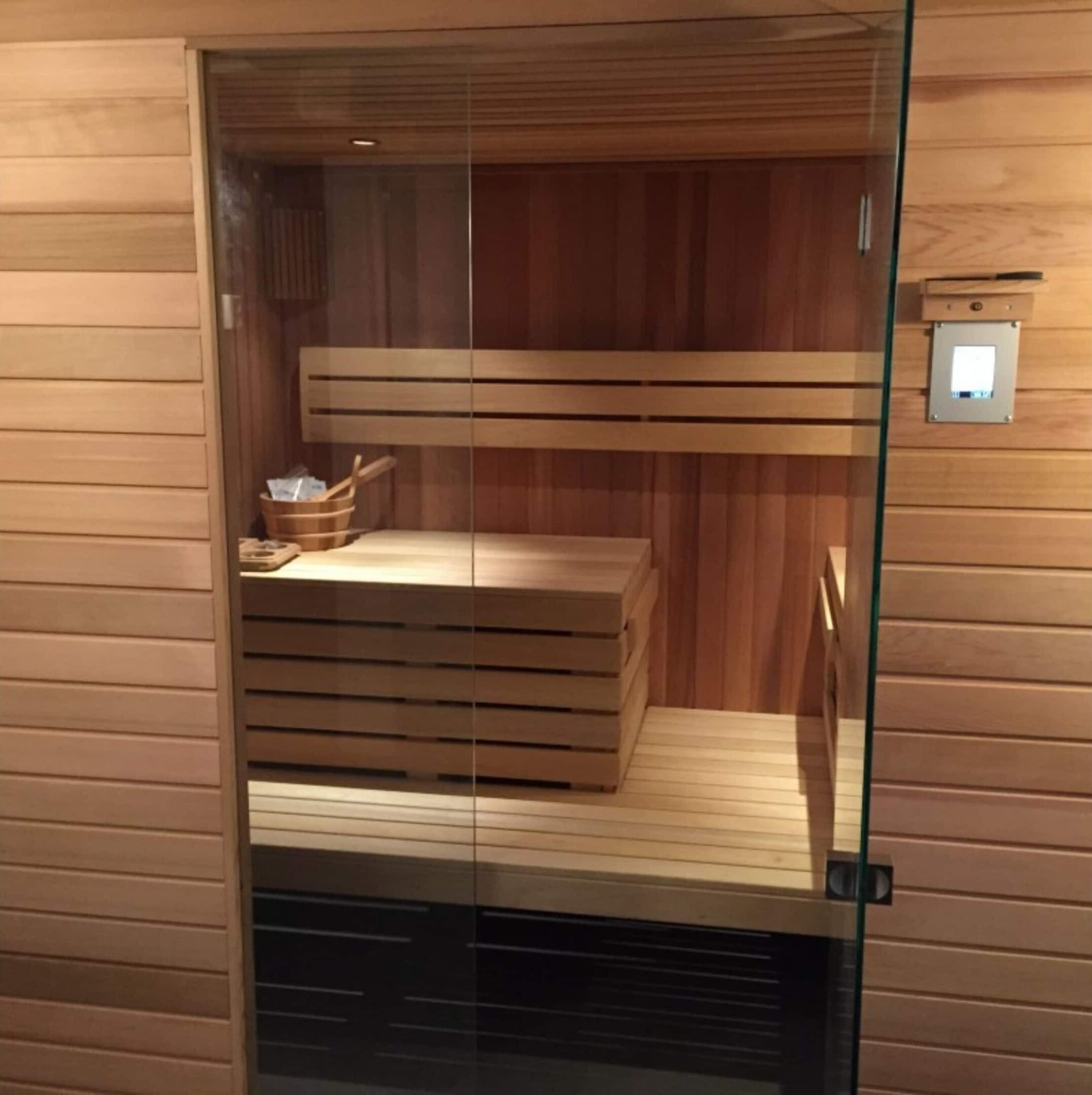 A sauna with wooden benches and a wooden bench with a basket.