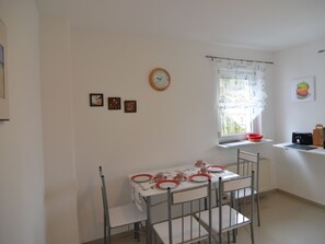 A small kitchen with a dining table set for two, a clock on the wall, and a window with a curtain. - Wonderful Apartment in Elpe With Garden (Olsberg)