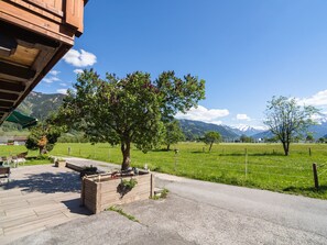 Relax in a serene garden setting under a shaded pergola, surrounded by lush greenery and vibrant flowers.