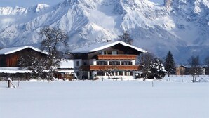 Ett hotell med en träfasad och en balkong, beläget med snötäckta berg som bakgrund.