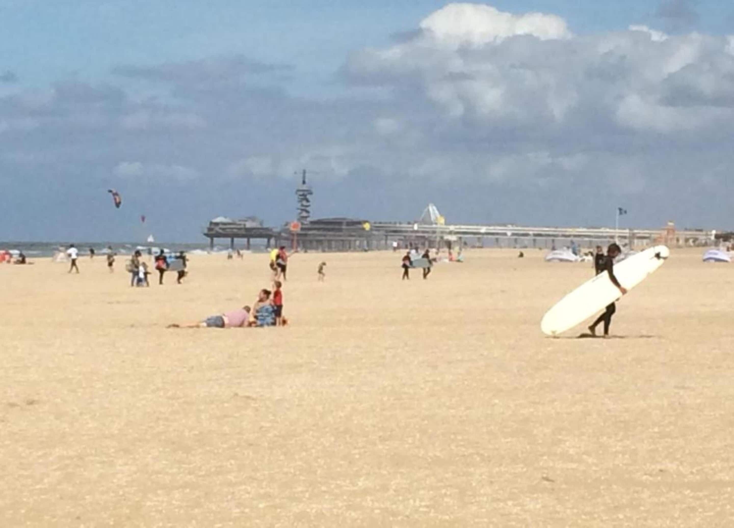 Una playa con gente, un muelle y una torre de salvavidas.