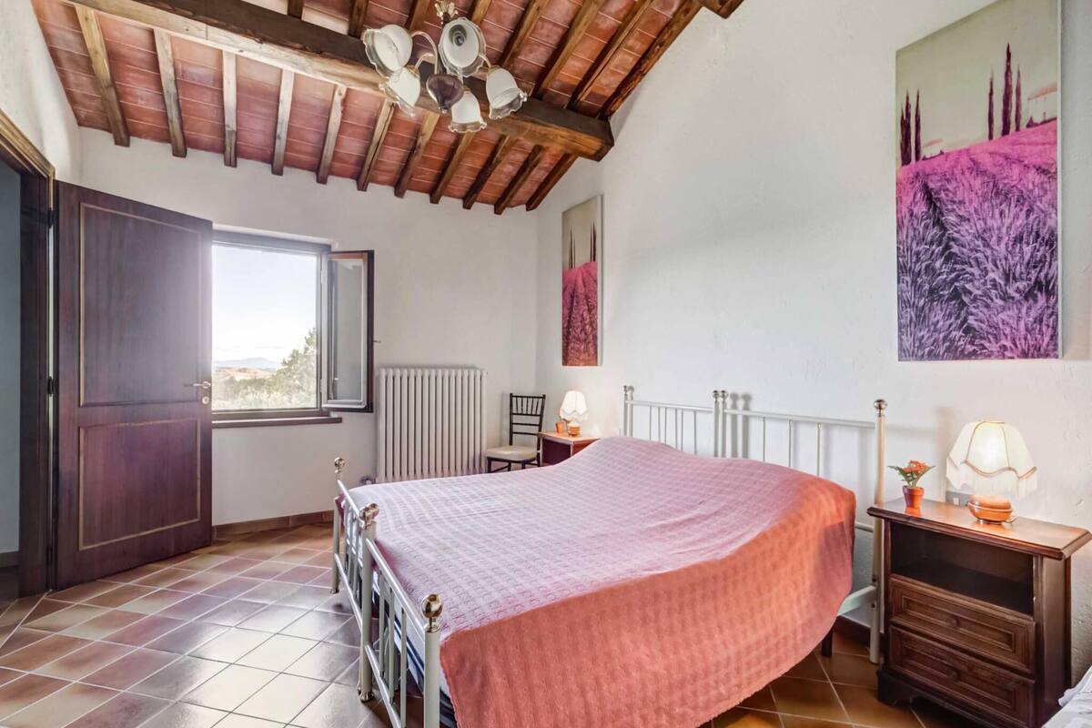A bedroom with a bed, a radiator, a window, and a painting on the wall.