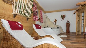 Un cuarto de spa con dos sillones reclinables, una bañera, paredes de madera y piso de madera.
