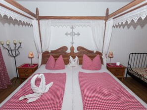 A traditional four-poster bed with a wooden headboard, white curtains, and a chandelier. - Alluring Holiday Home in Ubersee With Whirlpool (Uebersee)