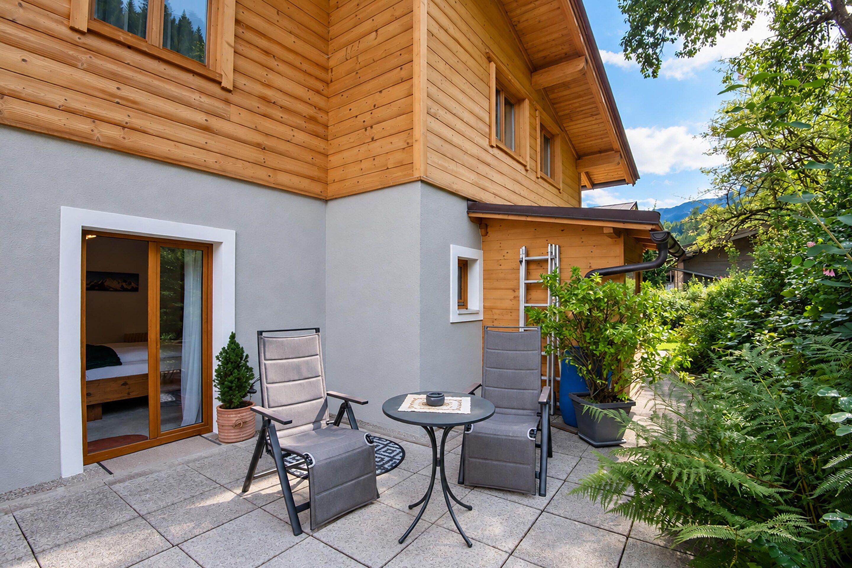 A wooden house with a patio area featuring two chairs and a table.