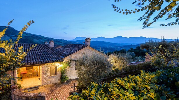 A stone house with a tiled roof, a small attached structure, and a view of distant mountains. - Gorgeous Apartment With Pool Near Sibillini Mountains (Monte San Martino)