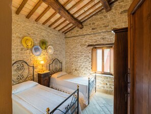A rustic bedroom with two beds, stone walls, wooden beams, and a window. - Gorgeous Apartment With Pool Near Sibillini Mountains (Monte San Martino)