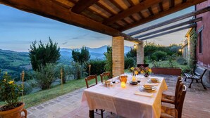 An outdoor dining area with a table set for two, surrounded by stone walls and potted plants. - Gorgeous Apartment With Pool Near Sibillini Mountains (Monte San Martino)