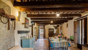 A rustic dining area with exposed wooden beams, a stone wall, and a table set for dining. - Gorgeous Apartment With Pool Near Sibillini Mountains (Monte San Martino)