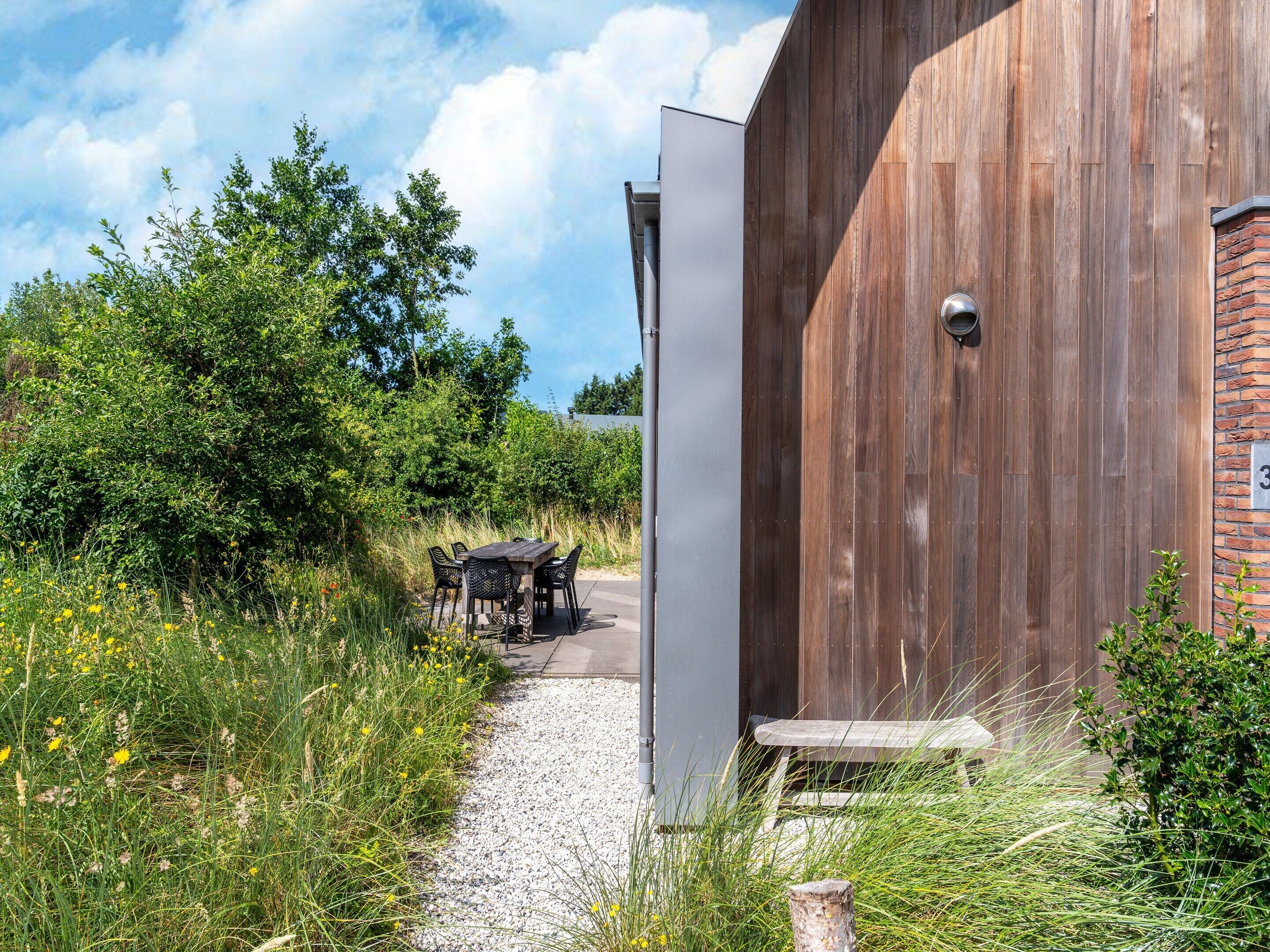 A wooden building with a gravel path leading to a table and chairs.