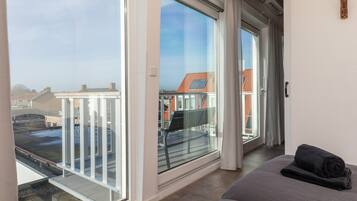 A hotel room with a large window, a balcony, and a bed with a rolled towel.