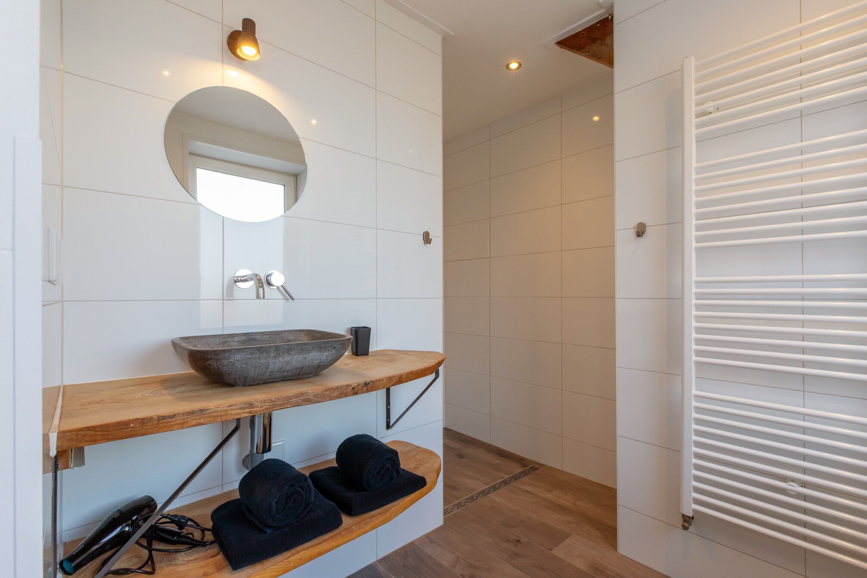Une salle de bain moderne avec un meuble-lavabo en bois, un grand miroir et un radiateur encastré.