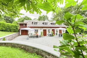 A traditional house with a stone wall, a gravel patio, and a wooden door. - House Situated on a Magnificent Estate (Durbuy)