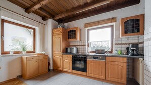 A kitchen with wooden cabinets, a microwave, an oven, and a dishwasher. - Beautiful Holiday Home in Viechtach With Views (Viechtach)