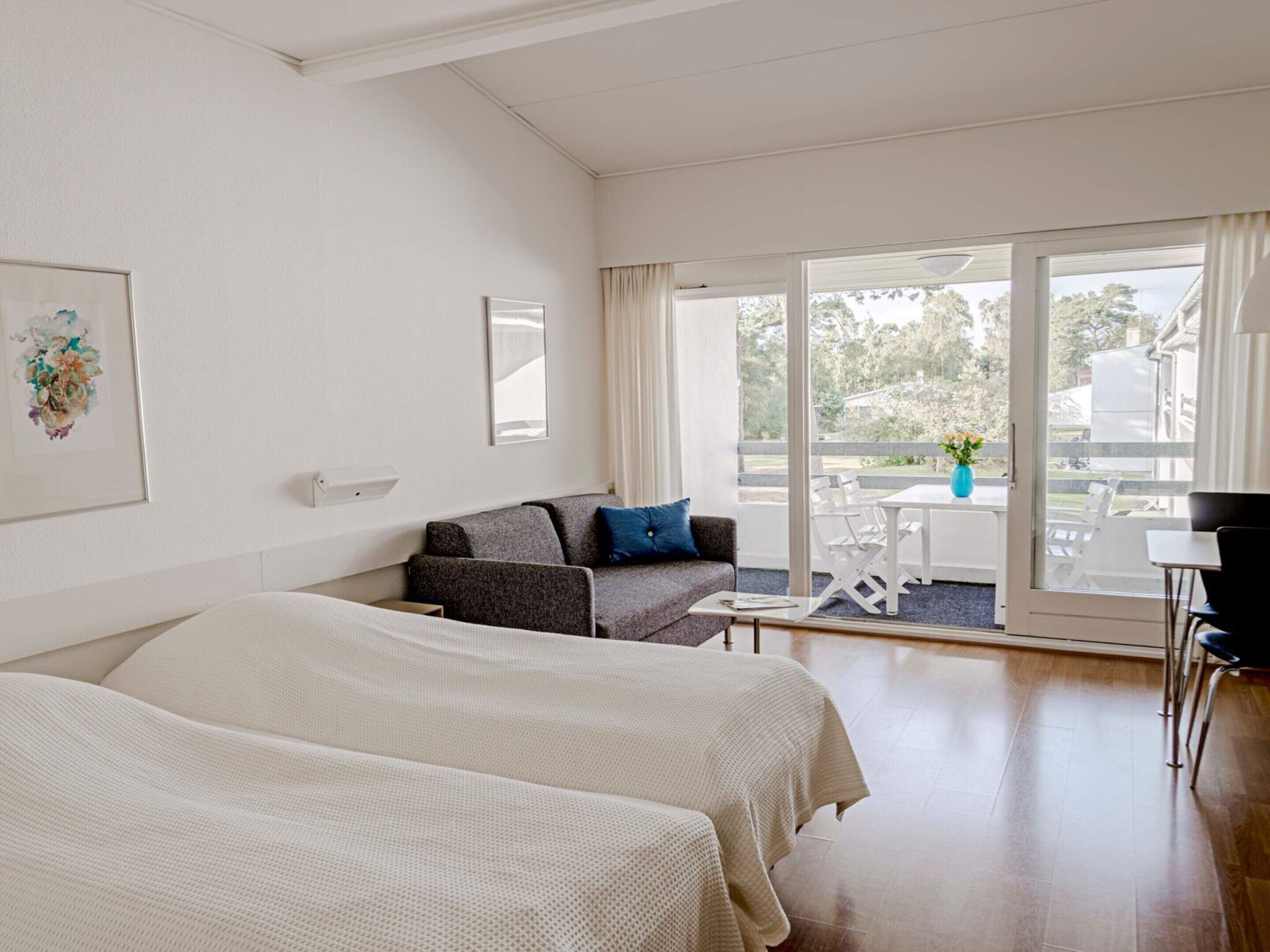 Habitación de hotel con dos camas, un sofá, una mesa y un balcón con vistas.