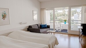 A hotel room with two beds, a sofa, a table, and a balcony with a view. - 2 Person Holiday Home in Nexo (Nexø)